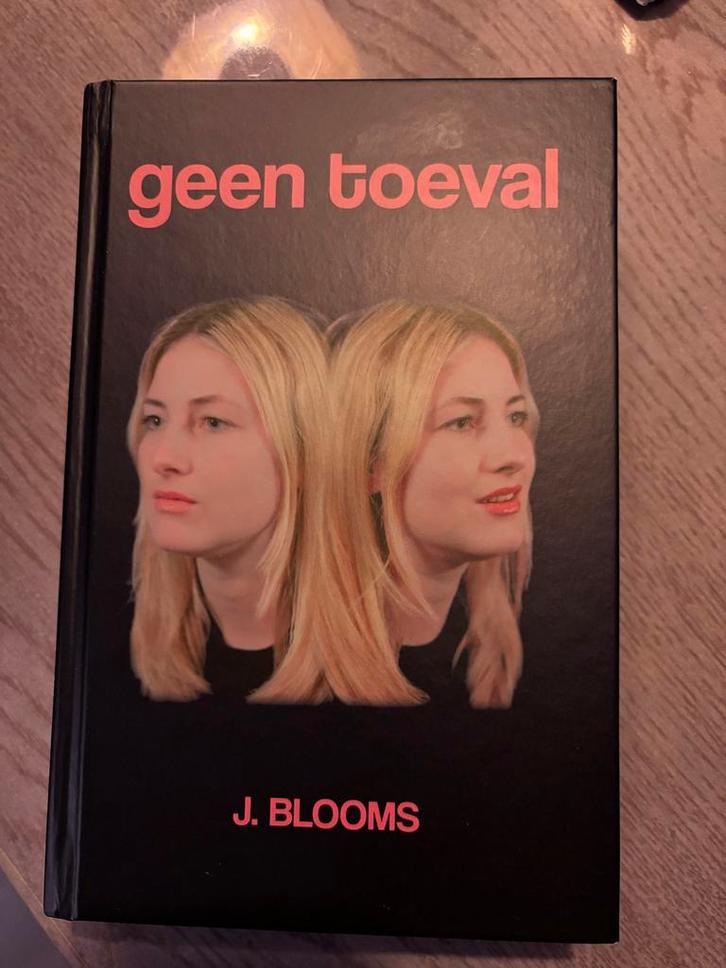 Geen Toeval - J. Blooms, Boeken, Romans, Zo goed als nieuw, Nederland, Ophalen of Verzenden
