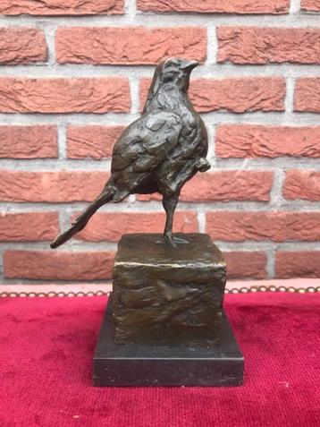 bronzen beeld van een vogel, staand op één potje