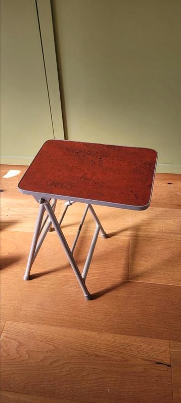 Klein verstelbaar tafeltje met rood blad beschikbaar voor biedingen