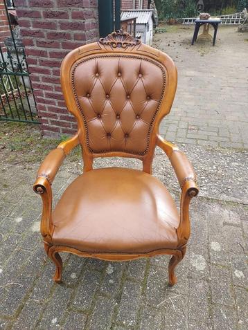 Barokstijl armstoel met bruin lederen bekleding.