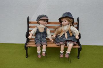 2 Vintage porseleinen poppen op een gietijzeren bankje 39 cm beschikbaar voor biedingen