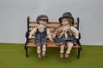 2 Vintage porseleinen poppen op een gietijzeren bankje 39 cm, Antiek en Kunst, Curiosa en Brocante, Ophalen of Verzenden