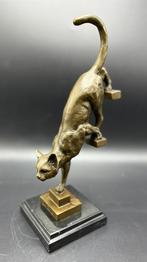 Bronzen kat die van de trap afloopt.