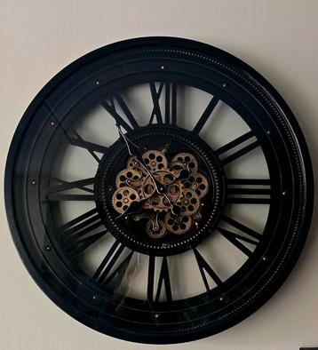 Grote metalen wandklok met draaiend binnenwerk.  beschikbaar voor biedingen