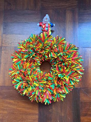 Krans in carnavalstinten met een clowntje.  Doorsnee 40 cm. beschikbaar voor biedingen
