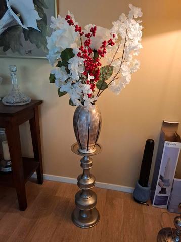 Zilverkleurige pilaar met vaas en bloemen. beschikbaar voor biedingen