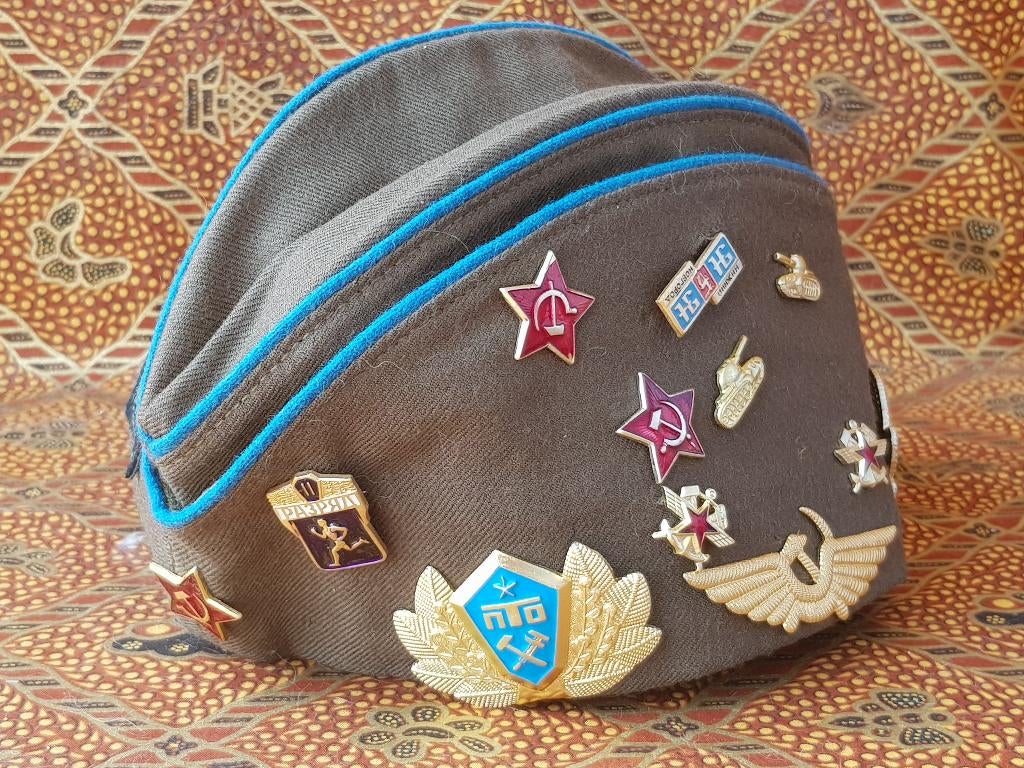 Oude militaria pet uit Rusland met speldjes en badges., Antiek en Kunst, Ophalen of Verzenden