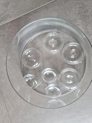 Grote glazen schaal met waxine drijvers en donuts beschikbaar voor biedingen