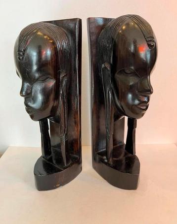 Twee houtsnijwerk hoofden, boekensteunen beschikbaar voor biedingen