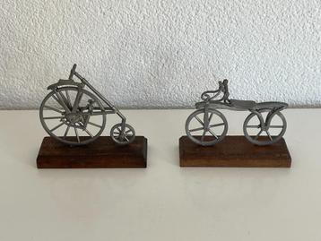 Twee metalen zilverkleurige miniatuur fietsen op hout beschikbaar voor biedingen