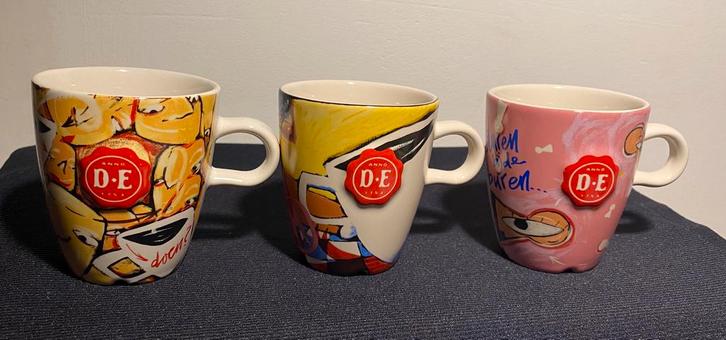 3 Verschillende mokjes van DE (burendag). H. 7,5 cm., Huis en Inrichting, Keuken | Servies, Zo goed als nieuw, Kop(pen) en/of Schotel(s)