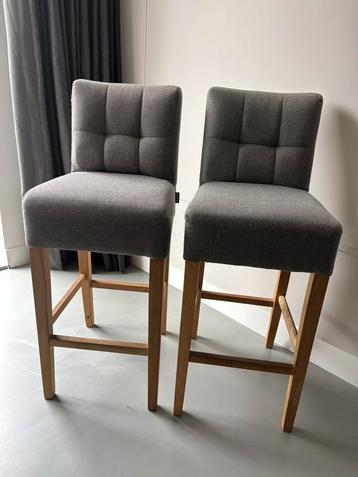 Twee comfortabele barkrukken – lichtgrijs met houten poten beschikbaar voor biedingen