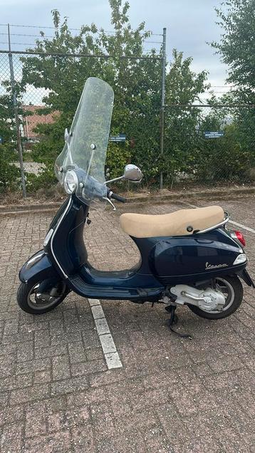 1ste eigenaar: blauwe Vespa LX50 4takt + slot en helm beschikbaar voor biedingen
